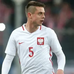 Piłkarz Borysiuk w białej koszulce z numerem 5 i godłem Polski.