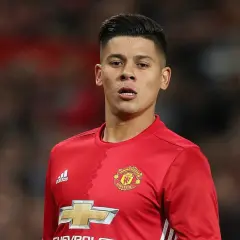 Piłkarz w czerwonej koszulce Manchester United, z logo klubu i Adidasa. Rojo wiek, skupiony na boisku.