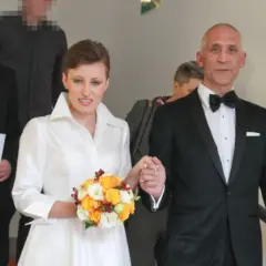 Szczęśliwa para młoda, Maciej i jego żona, idą schodami. Ona w białej sukni z bukietem, on w eleganckim smokingu.