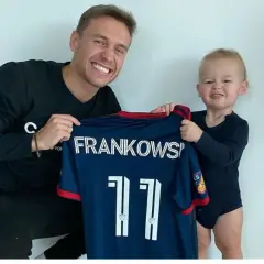 Frankowski piłkarz z synkiem prezentuje koszulkę z numerem 11.
