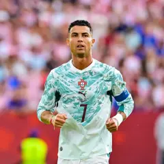 Ronaldo piłkarz w nowej koszulce Portugalii, gotowy do gry. Tłum kibiców na trybunach.