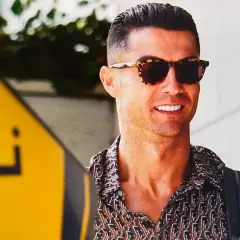 Uśmiechnięty Cristiano Ronaldo w okularach przeciwsłonecznych i wzorzystej koszuli. Zastanawiasz się, ile zarabia Ronaldo na minutę?