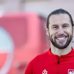 Uśmiechnięty Grzegorz Krychowiak w czerwonej bluzie reprezentacji Polski. Jego wiek to doświadczenie na boisku.