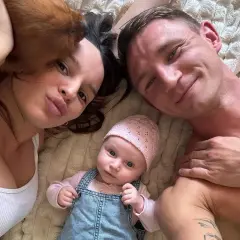 Uśmiechnięty Jakub Rzeźniczak z partnerką i ich maleńkim dzieckiem. Rodzina cieszy się wspólnymi chwilami.
