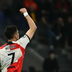 Piłkarz Jakub Moder z podniesioną pięścią, trzymający piłkę. Mimo niedawnej kontuzji, widać jego determinację.