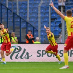 Piłkarze w żółto-czerwonych strojach świętują na boisku.