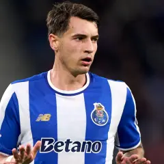 Piłkarz FC Porto, gdzie gra Kiwior, w niebiesko-białej koszulce, z uwagą obserwuje grę.