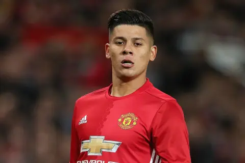 Piłkarz w czerwonej koszulce Manchester United, z logo klubu i Adidasa. Rojo wiek, skupiony na boisku.