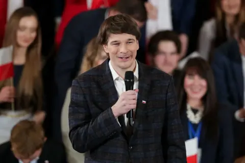 Daniel Nawrocki, którego wiek nie jest widoczny, przemawia do zgromadzonych ludzi.