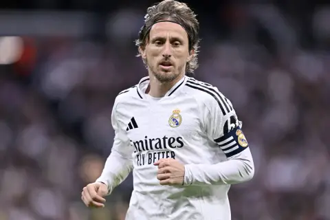 Chorwacki piłkarz Luka Modrić w białej koszulce Realu Madryt, z opaską kapitana na ramieniu, skupiony na grze.
