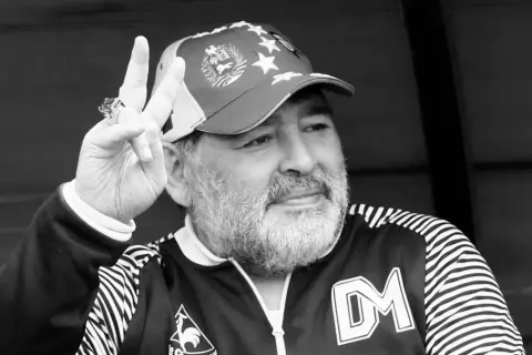 Diego Maradona, w czapce z gwiazdami, pokazuje znak pokoju. Ile lat ma Maradona? Tego nie wiemy, ale jego charyzma jest wieczna.
