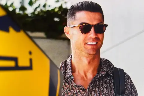 Uśmiechnięty Cristiano Ronaldo w okularach przeciwsłonecznych i wzorzystej koszuli. Zastanawiasz się, ile zarabia Ronaldo na minutę?