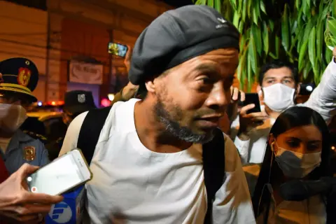 Ronaldinho w otoczeniu policji i tłumu, z telefonami skierowanymi na niego. Słynny piłkarz, którego losy potoczyły się w nieoczekiwany sposób, w tym do więzienia.