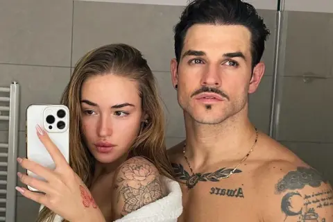 Seweryn Kiełpin i jego partnerka robią sobie selfie w łazience. Ona trzyma telefon, a on obejmuje ją ramieniem. Oboje mają tatuaże.