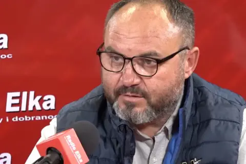 Piotr Rusiecki w kamizelce i okularach udziela wywiadu w Radiu Elka. Może opowiada o swojej żonie.