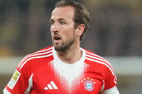 Piłkarz w czerwonej koszulce Bayernu Monachium, Harry Kane, wygląda na zaniepokojonego, być może z powodu kontuzji.
