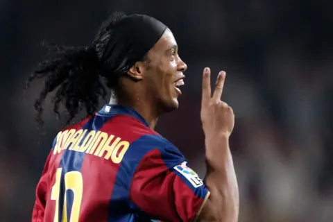 Ronaldinho w barwach FC Barcelony, klubu, w którym grał wiele lat. Pokazuje dwa palce, symbolizując zwycięstwo.