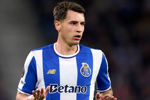 Piłkarz FC Porto, gdzie gra Kiwior, w niebiesko-białej koszulce, z uwagą obserwuje grę.