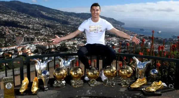 Cristiano Ronaldo z dumą prezentuje swoje liczne trofea, w tym Złote Piłki, na tle malowniczego krajobrazu Madery, swojego rodzinnego domu.