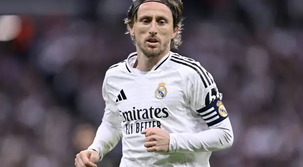Chorwacki piłkarz Luka Modrić w białej koszulce Realu Madryt, z opaską kapitana na ramieniu, skupiony na grze.