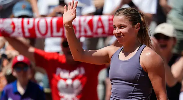 Maja Chwalińska, uśmiechnięta, macha do kibiców. W tle widać transparent z napisem "POLSKA".