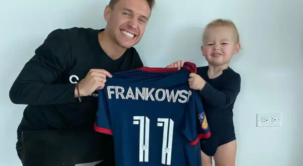Frankowski piłkarz z synkiem prezentuje koszulkę z numerem 11.