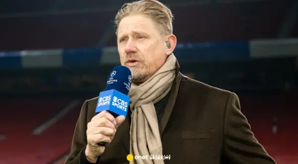 Antoni Schmeichel, z mikrofonem CBS Sports i szalikiem, komentuje mecz Ligi Mistrzów.