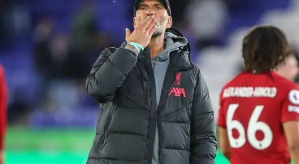 Trener Liverpoolu, Jürgen Klopp, posyła całusa kibicom. Obok niego stoi piłkarz z numerem 66.