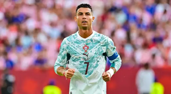 Ronaldo piłkarz w nowej koszulce Portugalii, gotowy do gry. Tłum kibiców na trybunach.
