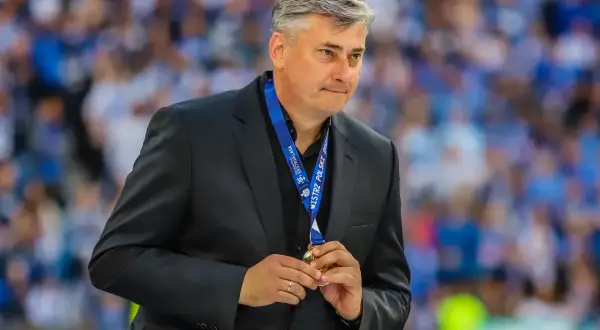 Maciej Skorża, po wygranej, trzyma medal. W tle tłum kibiców. Jego żona wspierała go w walce z chorobą.