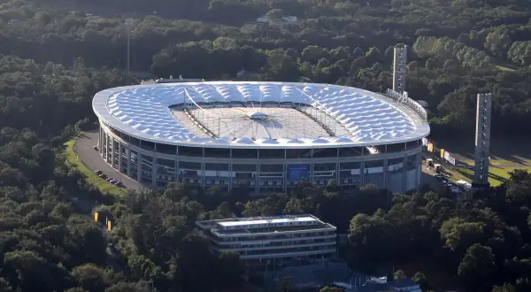 Stadion piłkarski otoczony drzewami, z charakterystycznym białym dachem.