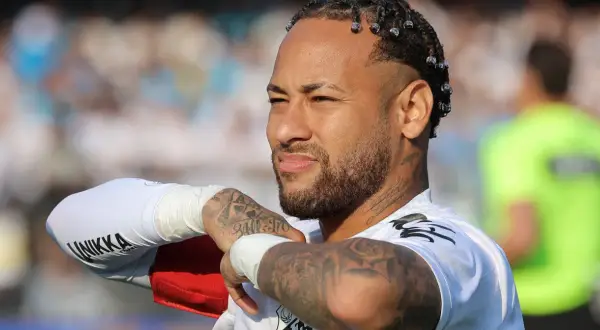 Neymar, z charakterystycznymi warkoczykami i tatuażami, w białej koszulce. Jego majątek budowany jest na boisku i poza nim.