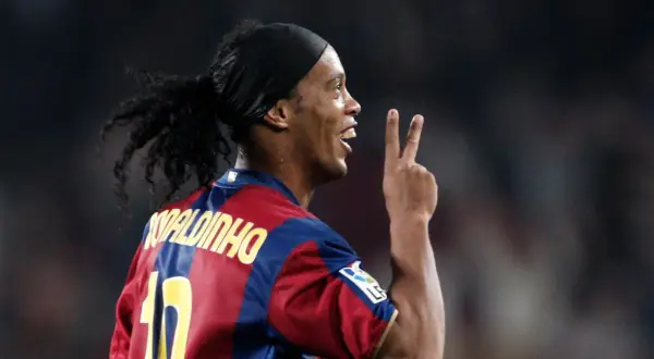 Ronaldinho w barwach FC Barcelony, klubu, w którym grał wiele lat. Pokazuje dwa palce, symbolizując zwycięstwo.