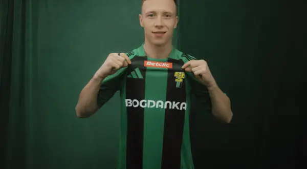 Młody piłkarz, którego miszor wiek sugeruje, że jest na początku kariery, prezentuje zielono-czarną koszulkę z logo Bogdanka.