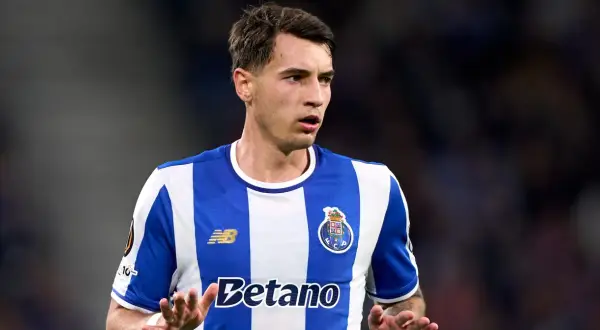 Piłkarz FC Porto, gdzie gra Kiwior, w niebiesko-białej koszulce, z uwagą obserwuje grę.