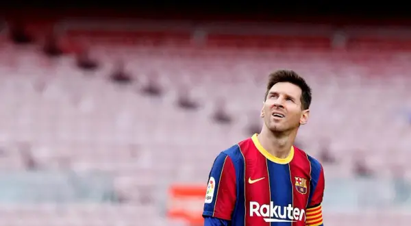 Messi w Barcelonie, w swoim charakterystycznym stroju, spogląda w górę na trybuny stadionu.