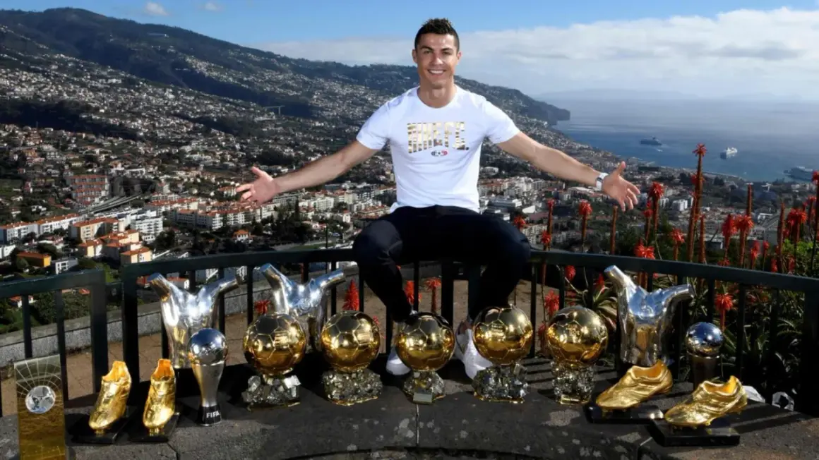 Cristiano Ronaldo z dumą prezentuje swoje liczne trofea, w tym Złote Piłki, na tle malowniczego krajobrazu Madery, swojego rodzinnego domu.