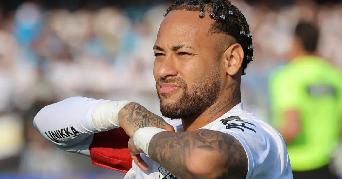 Neymar, z charakterystycznymi warkoczykami i tatuażami, w białej koszulce. Jego majątek budowany jest na boisku i poza nim.