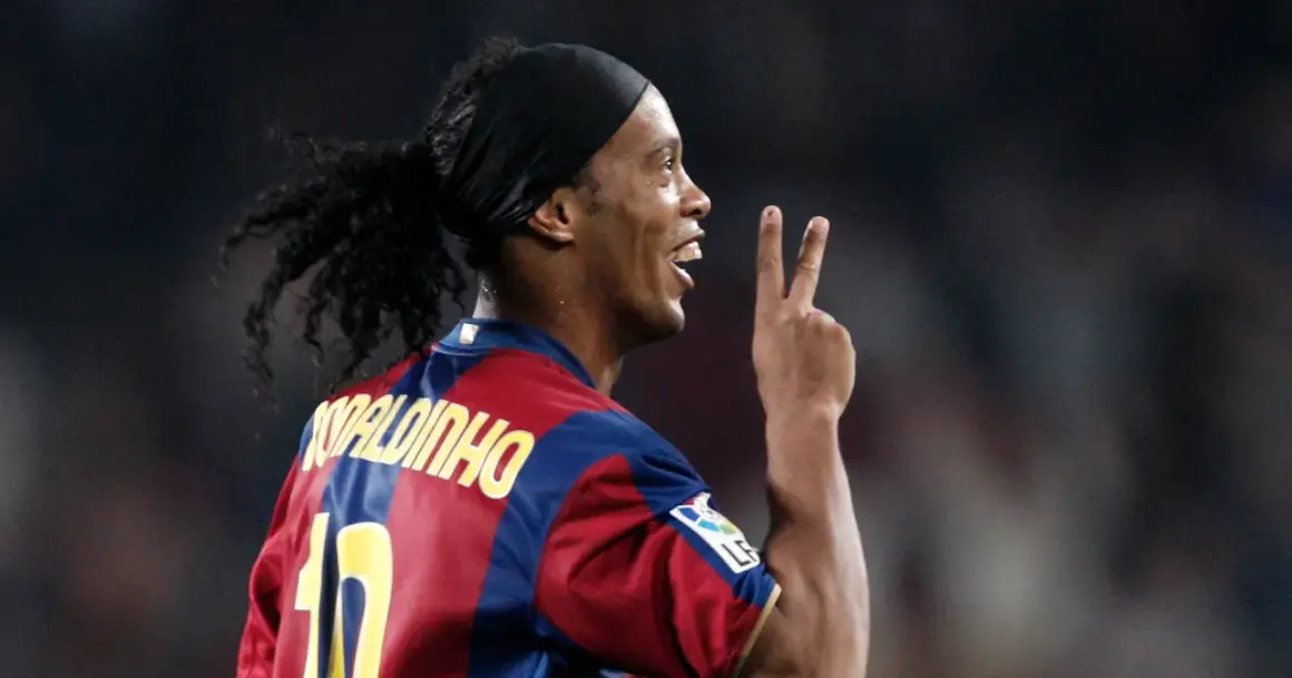 Ronaldinho w barwach FC Barcelony, klubu, w którym grał wiele lat. Pokazuje dwa palce, symbolizując zwycięstwo.