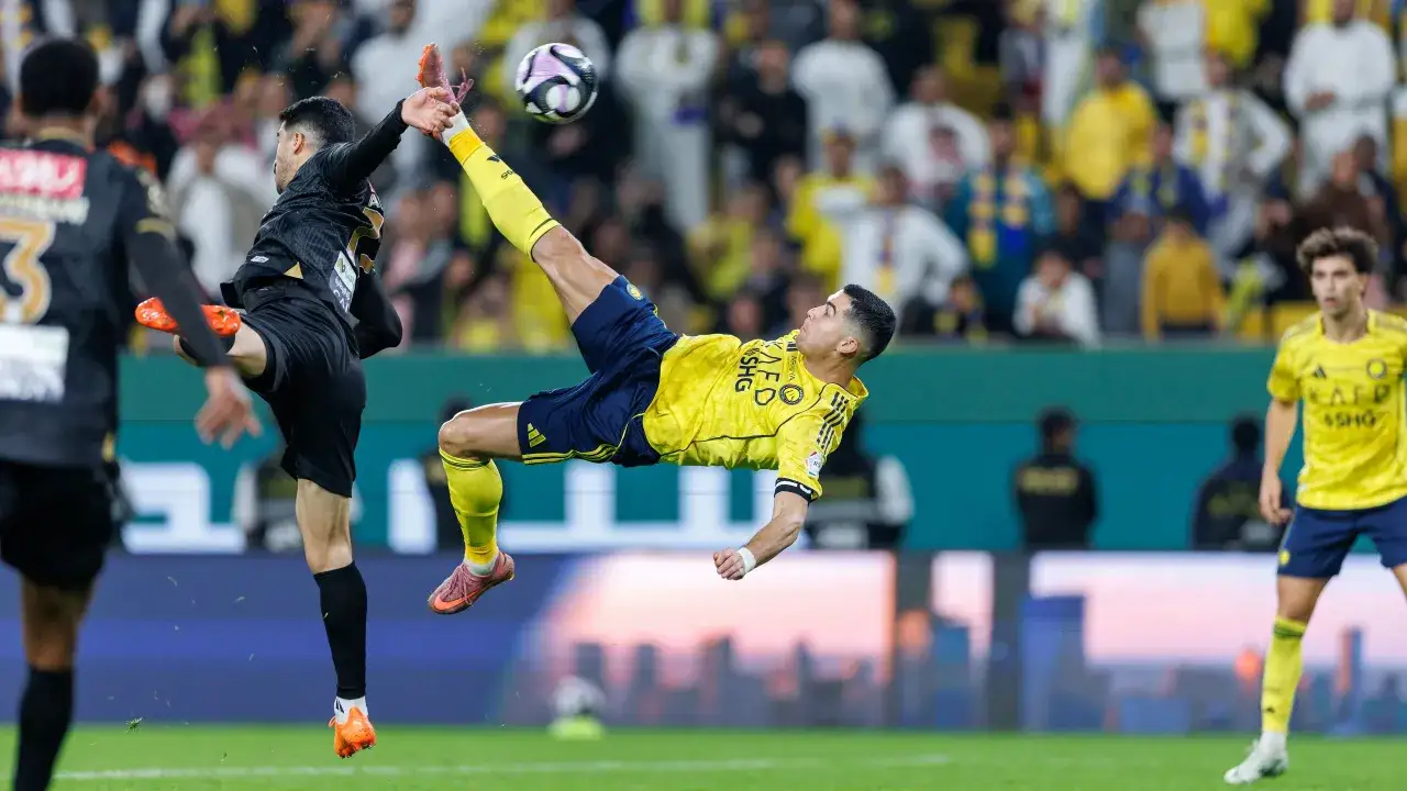 Piłkarz w żółtej koszulce wykonuje przewrotkę, próbując trafić w piłkę. To Ronaldo w akcji dla swojego klubu.