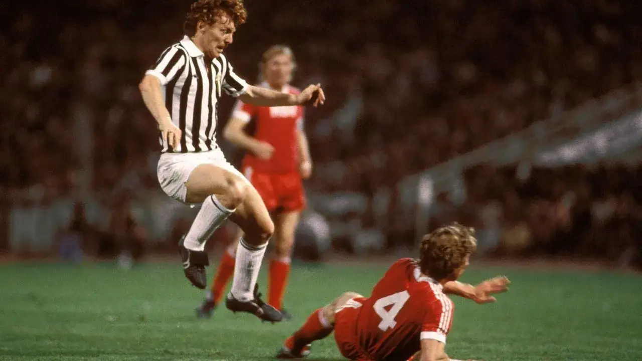 Piłkarz w pasiastej koszulce, Zbigniew Boniek, w akcji. Jego wiek nie przeszkadza mu w dynamicznej grze.