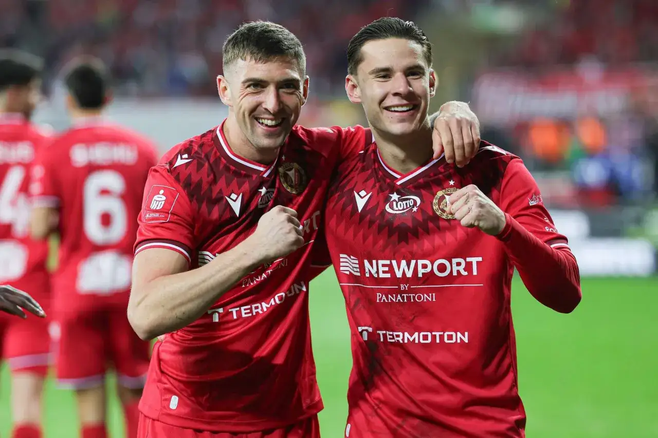 Dwóch piłkarzy w czerwonych koszulkach świętuje zwycięstwo. Radość na ich twarzach mówi wszystko, kiedy gra ekstraklasa!