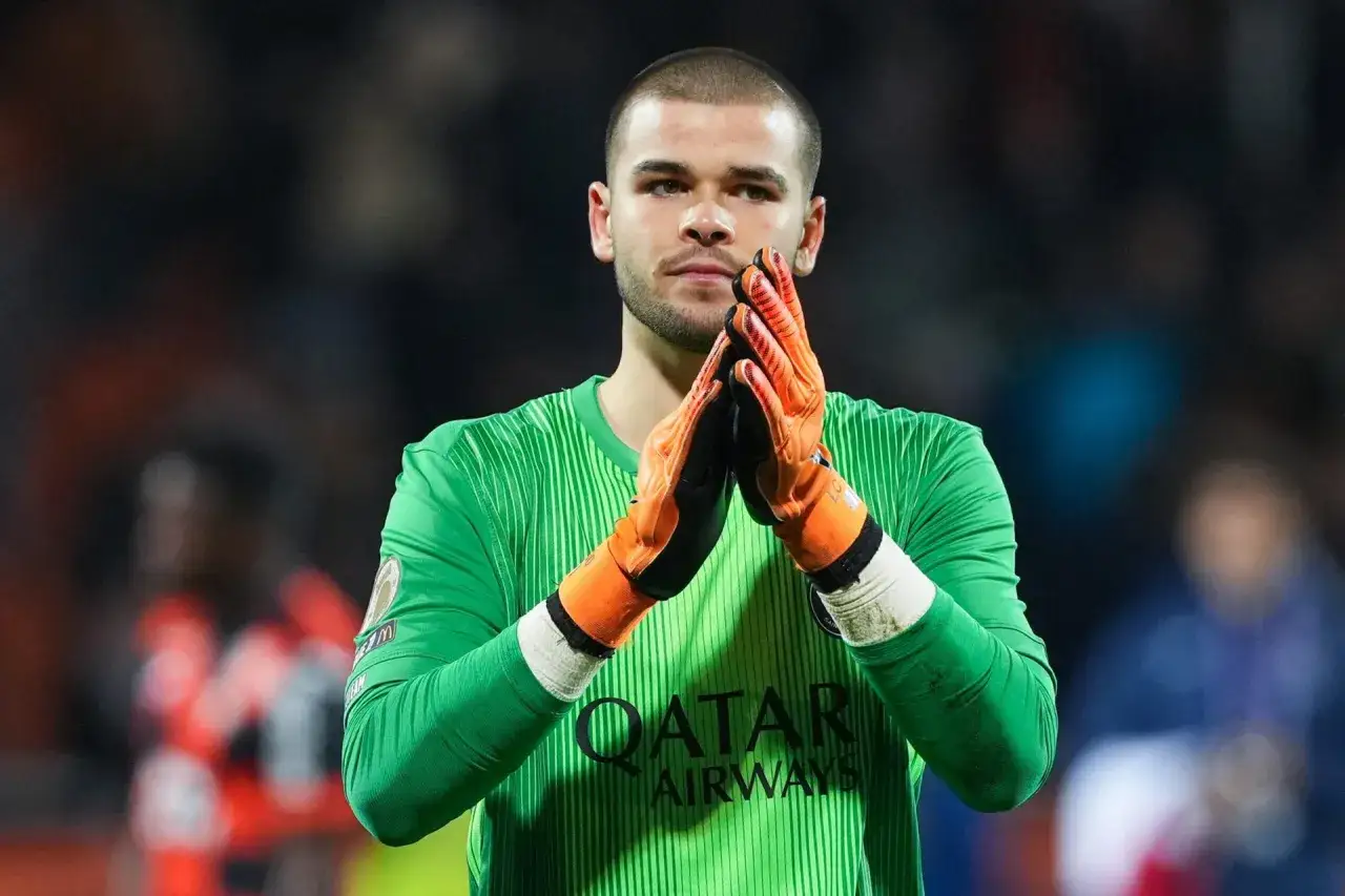 Bramkarz PSG w zielonej koszulce z pomarańczowymi rękawicami, klaskający.