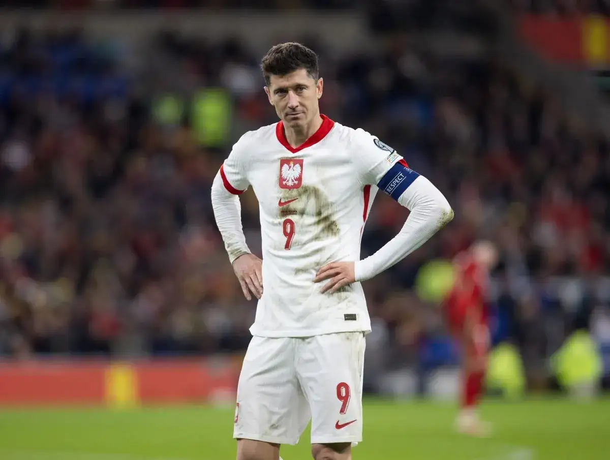 Robert Lewandowski w białej koszulce reprezentacji Polski, z numerem 9. Na rękawie opaska 