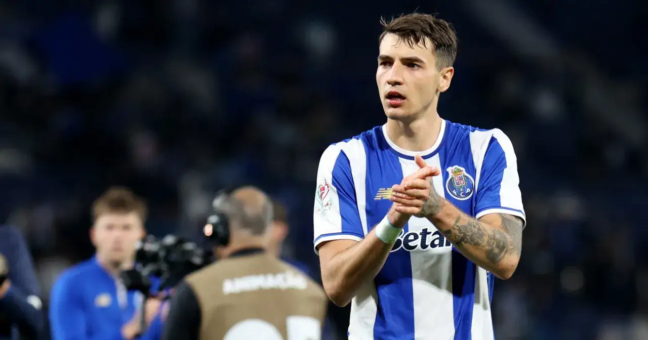 Piłkarz FC Porto, gdzie gra Kiwior, w niebiesko-białej koszulce, z dłońmi złożonymi w geście uznania.