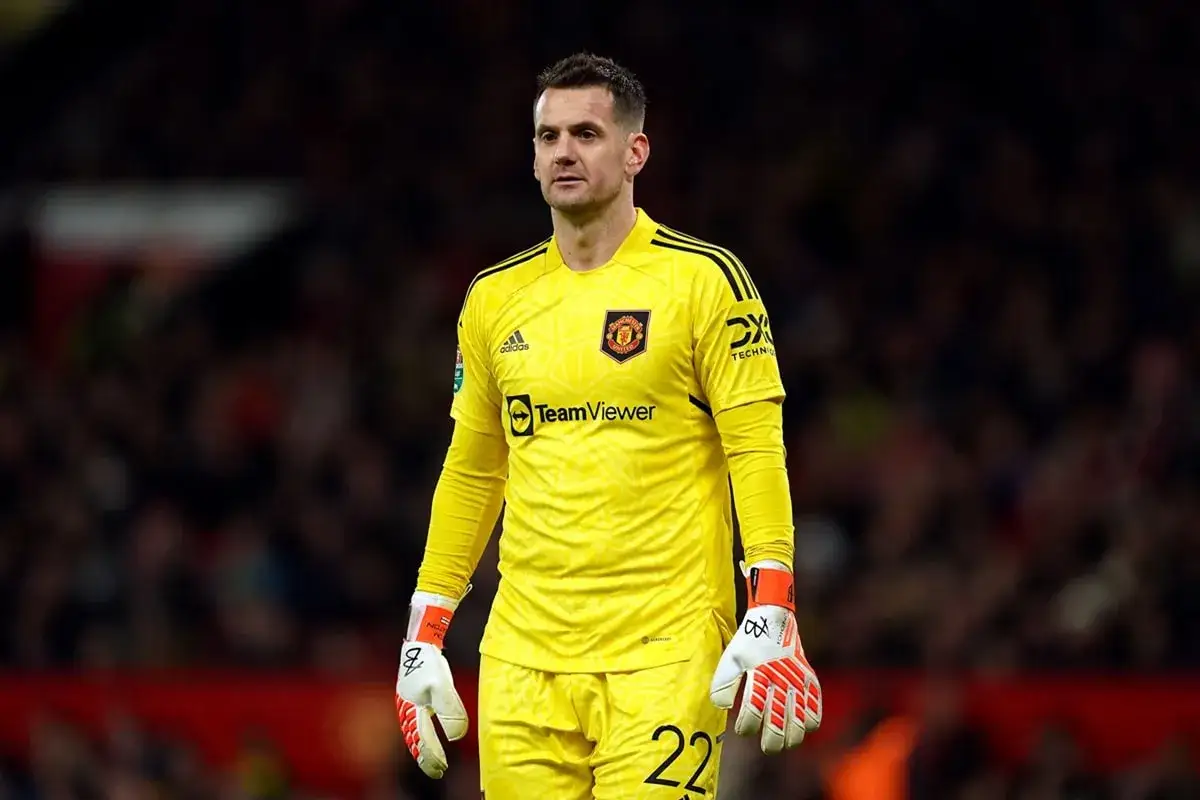 Bramkarz Tom Heaton w żółtym stroju Manchester United, z numerem 22 na spodenkach, gotowy do obrony.