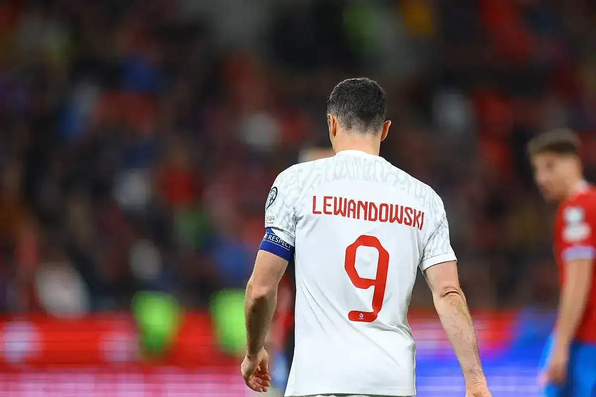 Piłkarz Robert Lewandowski, numer 9, na białej koszulce z czerwonym napisem.