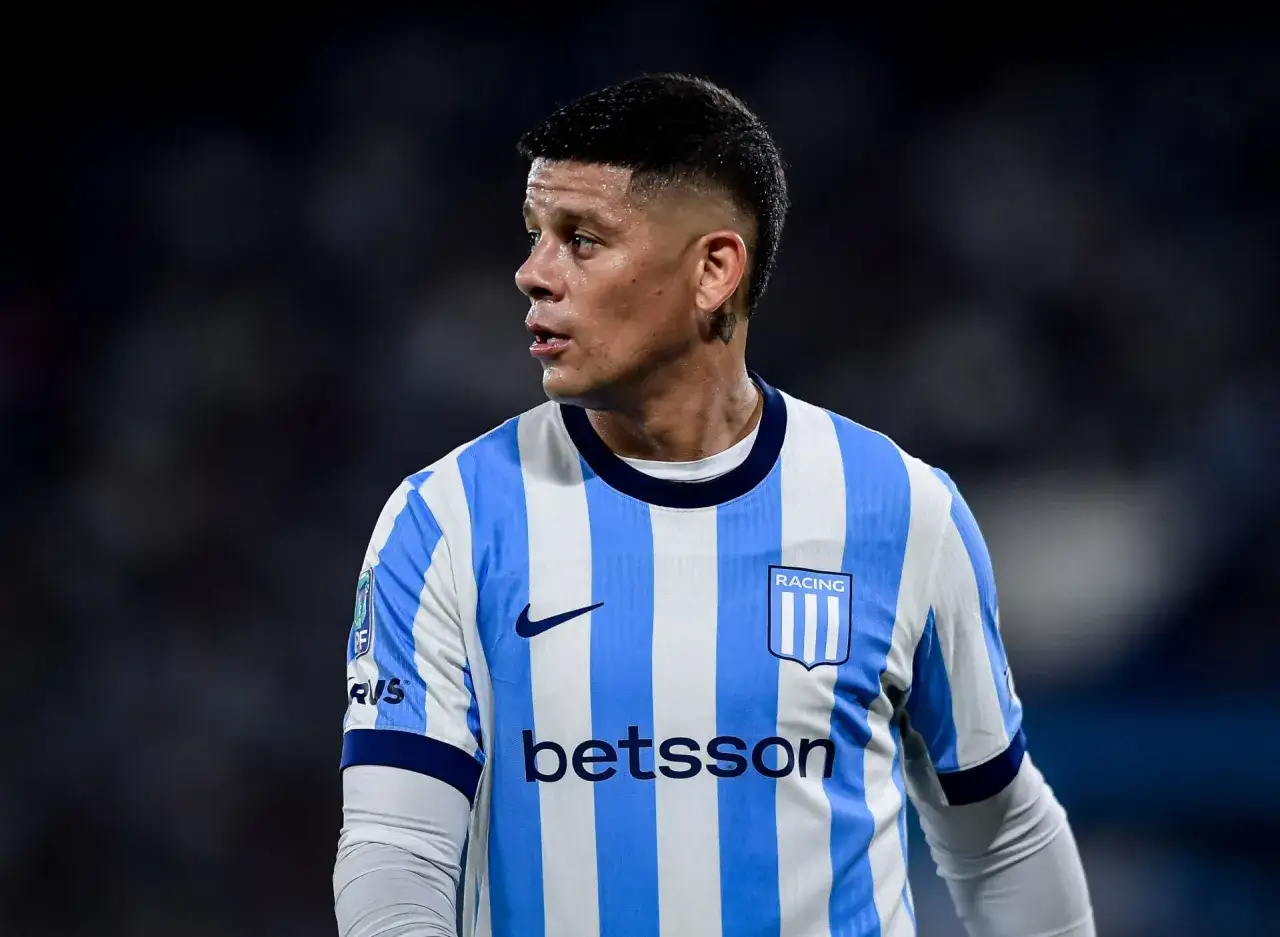Piłkarz w koszulce Racing Club, z logo Betsson. Rojo wiek, skupiony na boisku.