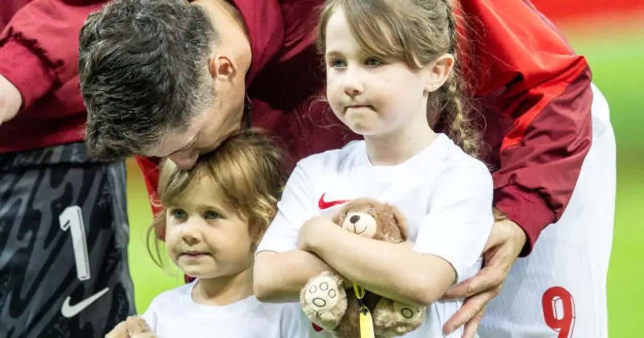 Robert Lewandowski całuje w głowę córkę Laurę, podczas gdy druga córka tuli misia.