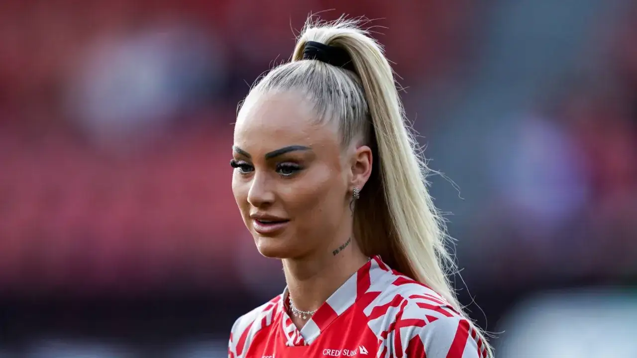 Piłkarka z blond kucykiem, w czerwono-białej koszulce, z tatuażem na szyi 
